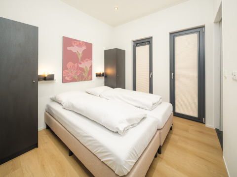 Moderne soveværelse på Essenburgh Lodge med dobbeltseng, skarpt lys og minimalistisk indretning i Veluwepark de Bosgraaf, Holland.