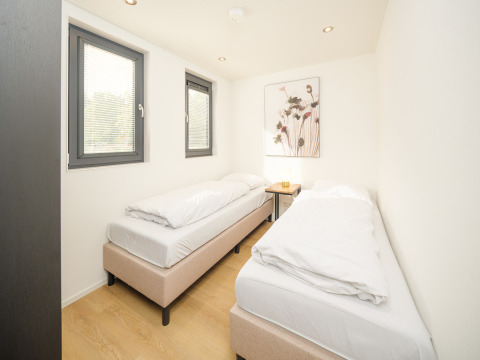 Bright bedroom with two single beds, large windows, and minimalist decor at Essenburgh lodge, Veluwepark de Bosgraaf.