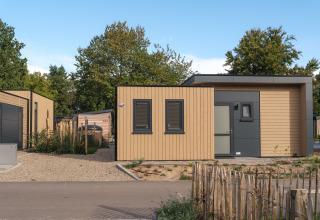 Moderne lodge med træfacade, terrasse og sauna på Veluwepark de Bosgraaf i Holland, omgivet af natur.