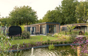 Moderne Lodge Essenburgh Comfort mit Whirlpool und Sauna im Veluwepark de Bosgraaf, von Garten umgeben.