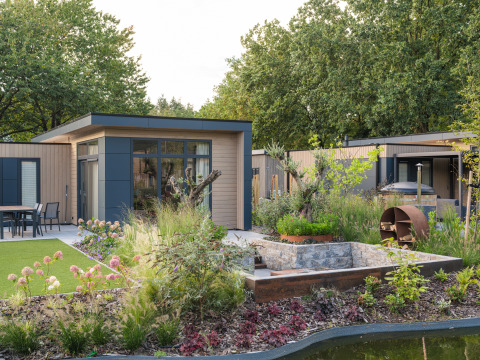 Moderne Lodge mit Garten, Blumen und viel Grün im Veluwepark de Bosgraaf in den Niederlanden.