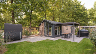 Außenansicht der Doornenburg Lodge Comfort mit moderner Terrasse, Hot Tub und Sauna im Grünen.