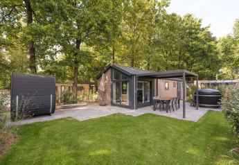 Außenansicht der Doornenburg Lodge Comfort mit moderner Terrasse, Hot Tub und Sauna im Grünen.