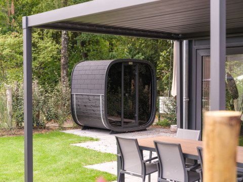 Modern lodge with outdoor sauna and patio set at Veluwepark de Bosgraaf, Netherlands, in a green setting.