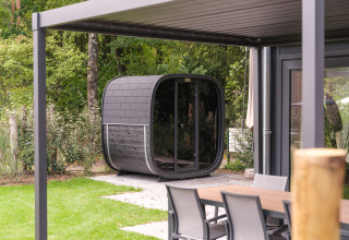Moderne Lodge mit Außensauna und Sitzbereich im Veluwepark de Bosgraaf, Niederlande, im Grünen.