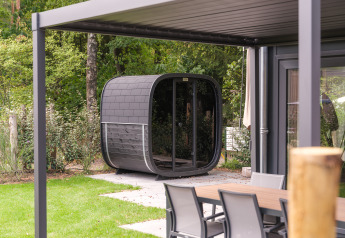 Lodge moderno con sauna esterna e tavolo da giardino al Veluwepark de Bosgraaf, Paesi Bassi, immerso nel verde.