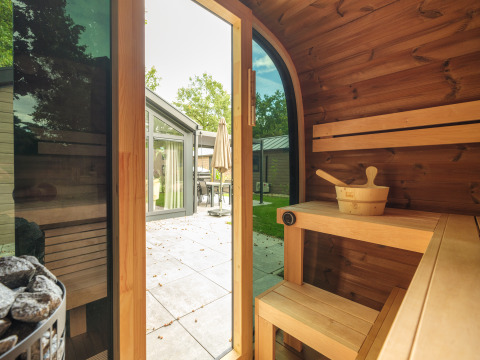 Blick aus einer Holzsauna mit offener Tür zur Terrasse im Doornenburg Lodge Comfort in den Niederlanden.