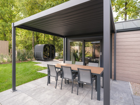 Covered patio at Doornenburg Lodge Comfort with dining table, chairs, and garden view at Veluwepark.