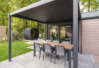 Covered patio at Doornenburg Lodge Comfort with dining table, chairs, and garden view at Veluwepark.