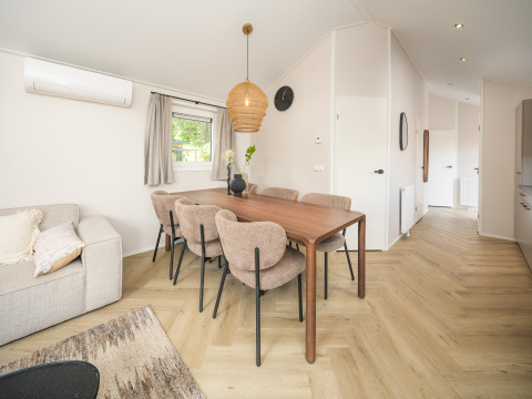 Modern dining area with six chairs and a wooden table in Doornenburg Lodge Comfort at Veluwepark de Bosgraaf.