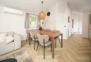 Comedor moderno con seis sillas y mesa de madera en Doornenburg Lodge Comfort en Veluwepark de Bosgraaf.