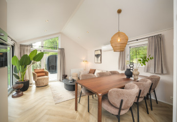 Zona giorno luminosa della Doornenburg Lodge Comfort con tavolo da pranzo e ampie finestre in Olanda.