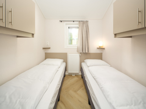 Twee eenpersoonsbedden in een lichte kamer van Doornenburg Lodge Comfort, Veluwepark de Bosgraaf, Nederland.