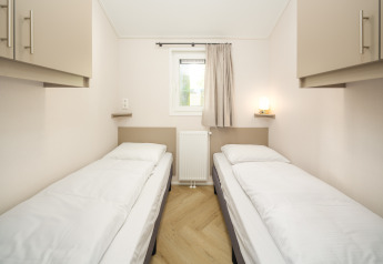 Two single beds in a bright room at Doornenburg Lodge Comfort, Veluwepark de Bosgraaf, Netherlands.