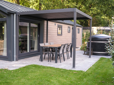 Terrasse der Doornenburg Lodge Comfort mit Esstisch, Stühlen und Hot Tub im Veluwepark de Bosgraaf, Niederlande.