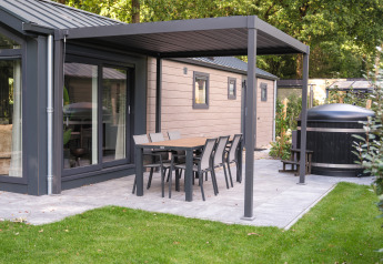 Terraza exterior de Doornenburg Lodge Comfort con mesa, sillas y jacuzzi en Veluwepark de Bosgraaf, Países Bajos.