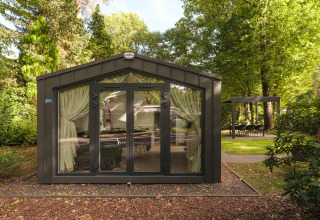 Modernes Chalet mit Glasfront und Vorhängen im Grünen im Veluwepark de Bosgraaf, Niederlande.