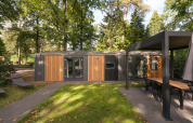 Modern Cozy Chalet lodge at Veluwepark de Bosgraaf in the Netherlands, surrounded by lush trees.