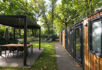 Zona exterior en Cozy Chalet en Veluwepark de Bosgraaf, Países Bajos, con comedor y vegetación abundante.