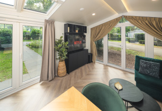 Soggiorno luminoso nel Cozy Chalet a Veluwepark de Bosgraaf, Paesi Bassi, con grandi finestre e verde.
