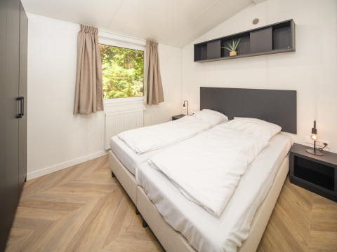 Moderne soveværelse i Cozy Chalet ved Veluwepark de Bosgraaf i Holland med dobbeltseng og naturligt lys.