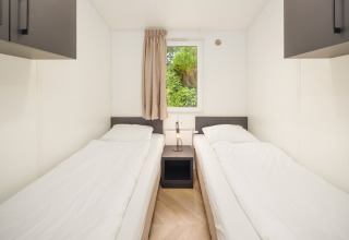 Helles Schlafzimmer mit zwei Einzelbetten im Cozy Chalet im Veluwepark de Bosgraaf in den Niederlanden.