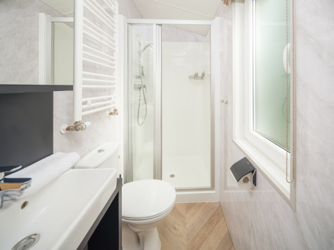 Bagno moderno e compatto con doccia, WC, lavabo e finestra presso Cozy Chalet al Veluwepark de Bosgraaf.