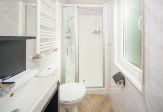 Bagno moderno e compatto con doccia, WC, lavabo e finestra presso Cozy Chalet al Veluwepark de Bosgraaf.