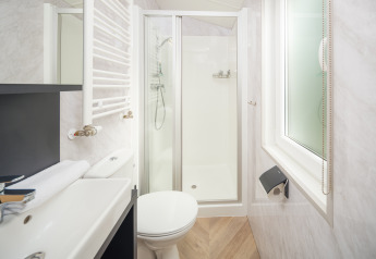 Salle de bain moderne et compacte avec douche, toilettes, lavabo et fenêtre au Cozy Chalet du Veluwepark de Bosgraaf.