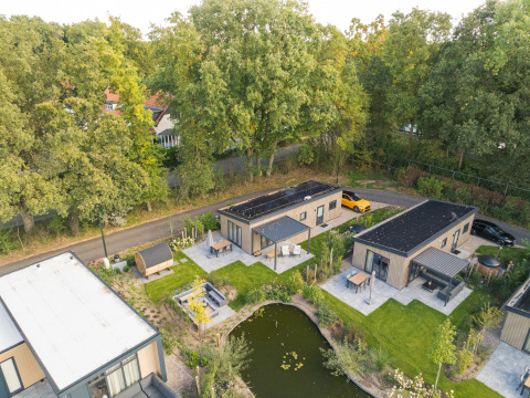 Luchtfoto van Loevestein Deluxe lodge met hottub & sauna aan een vijver in Veluwepark de Bosgraaf, Nederland.