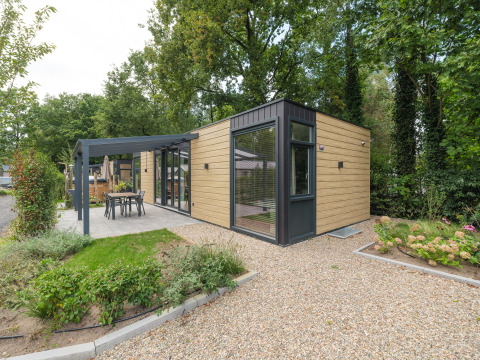 Moderne Rosendael Comfort Lodge mit Whirlpool, Holzverkleidung und Terrasse im grünen Gartenbereich.