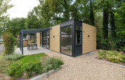 Moderne Rosendael Comfort lodge met hottub, houten gevel en terras in een groene tuinomgeving.