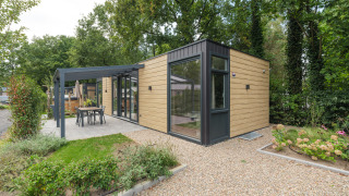 Lodge moderno Rosendael Comfort con vasca idromassaggio, facciata in legno e patio in giardino verde.