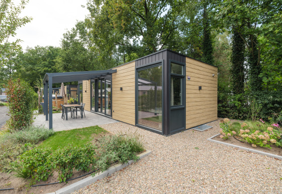 Moderne Rosendael Comfort Lodge mit Whirlpool, Holzverkleidung und Terrasse im grünen Gartenbereich.