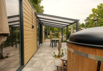 Buiten terras bij Rosendael Comfort lodge met overkapping en hottub op Veluwepark de Bosgraaf, Nederland.