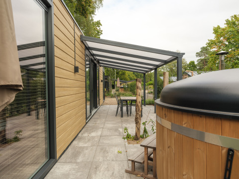 Buitenterras bij Rosendael Comfort lodge met overkapping en hottub in Veluwepark de Bosgraaf, Nederland.