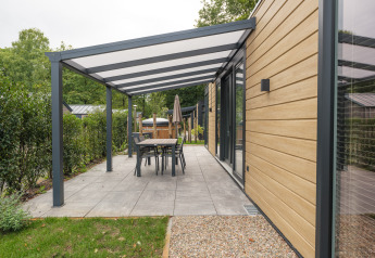 Moderne lodge med overdækket terrasse og havebord ved Rosendael Comfort med hottub, Veluwepark de Bosgraaf, Holland.