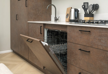 Modern kitchen with open built-in dishwasher, black faucet, stove, and utensils at Rosendael Comfort lodge.