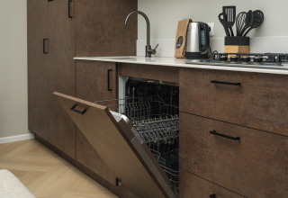 Moderne keuken met open ingebouwde vaatwasser, fornuis en accessoires in Rosendael Comfort lodge.