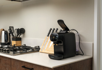 Modern kitchen counter at Rosendael Comfort with coffee machine, knives, and stove at Veluwepark de Bosgraaf.
