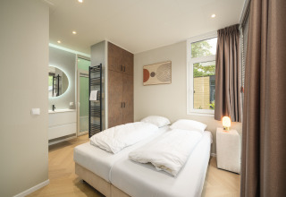 Modernes Schlafzimmer im Rosendael Comfort mit Doppelbett und Bad im Veluwepark de Bosgraaf, Niederlande.