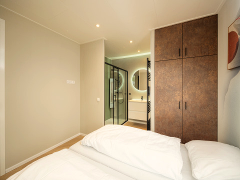 Camera da letto moderna con letto matrimoniale, armadio e bagno privato al Rosendael Comfort di Veluwepark de Bosgraaf.