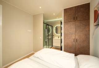 Camera da letto moderna con letto matrimoniale, armadio e bagno privato al Rosendael Comfort di Veluwepark de Bosgraaf.