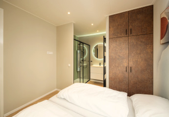 Chambre de lodge moderne avec lit double, armoire et salle de bain attenante à Rosendael Comfort au Veluwepark de Bosgraaf.