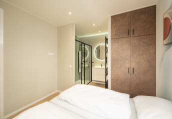 Moderne lodge-soveværelse med dobbeltseng, garderobeskab og eget badeværelse på Rosendael Comfort i Veluwepark de Bosgraaf.
