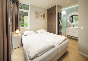 Dormitorio moderno en Rosendael Comfort con jacuzzi en Veluwepark de Bosgraaf, Países Bajos, decoración luminosa.