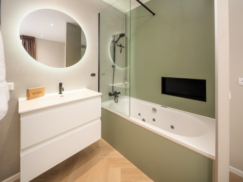 Bagno moderno con specchio rotondo, lavabo bianco e vasca idromassaggio al Rosendael Comfort, Veluwepark de Bosgraaf, Paesi Bassi.