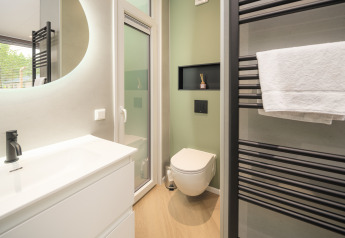 Moderne badeværelse på Rosendael Comfort med vægmonteret toilet og håndklædetørrer i Veluwepark de Bosgraaf.