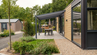 Moderne Lodge mit Holzfassade, überdachter Terrasse und Garten im Veluwepark de Bosgraaf in den Niederlanden.