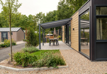 Lodge moderne avec façade en bois, terrasse couverte et salle à manger au Veluwepark de Bosgraaf, Pays-Bas.